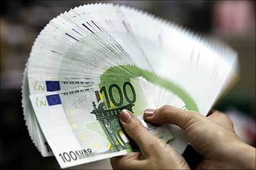 An employee counts Euro notes.