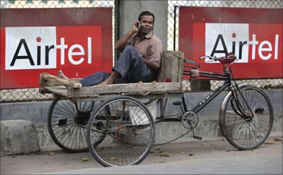A man talks on a mobile phone in front of advertisements of Bharti Airtel.