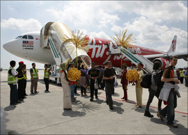 Passengers aboard AirAsia's maiden flight from London to Kuala Lumpur walk on the tarmac.