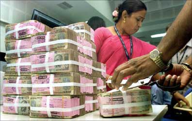 A bank staff is arranging stacks of rupee.