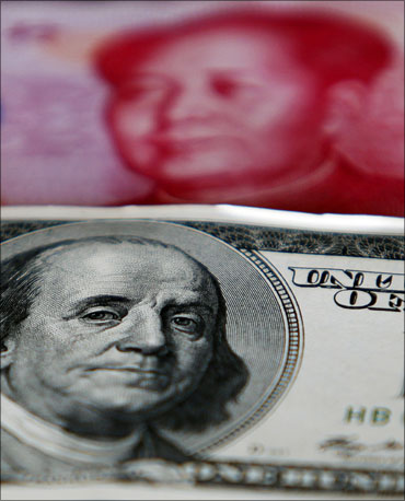 A yuan banknote is displayed behind a US dollar banknote for the photographer at a money changer's place.