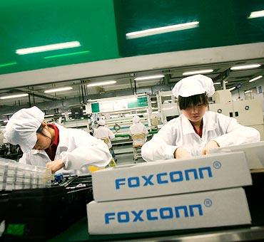 Workers walk on a street outside factory buildings at Foxconn in the township of Longhua.