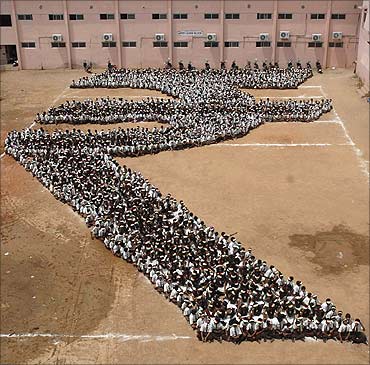 Students make a formation of the new symbol of the Indian rupee at a school in Chennai.