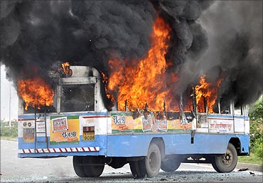 A passenger bus is set on fire during a protest by farmers demanding higher compensation for land.