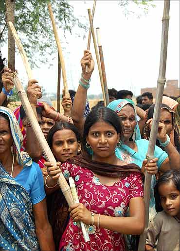 Stick-wielding protesters, mostly women, demonstrate as they demand higher compensation for land.