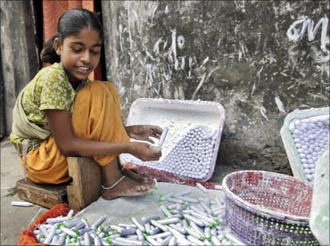Laxmi packs lime paste tubes outside her house in a slum area in Mumbai.