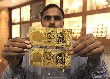A salesman displays gold plates in the form of the Indian rupee note at a jewellery showroom.