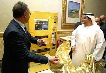 Ex Oriente Lux CEO Thomas Geissler (L) and an Emirati official unveil a gold-plated ATM.