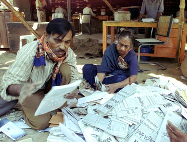 Postal employees sort mail in an open area at the main post office of Bhuj in Gujarat.