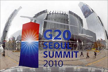 People are reflected on a sculpture in front of the Coex Convention Centre, the venue of the G20 summit.