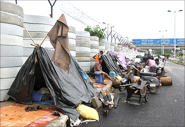 Labourers rest inside their makeshift tents outside the boundary wall of Commonwealth Games village.