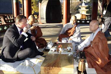 Britain's Prime Minister David Cameron (L) drinks tea with monks at the Bongeunsa temple in Seoul.