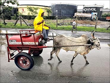 A worker transporting kerosene in a bullock cart travels past Indian Oil Corporation's fuel depot.