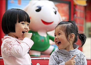 Two children pose in front of the Asian Games mascot in Guangzhou.