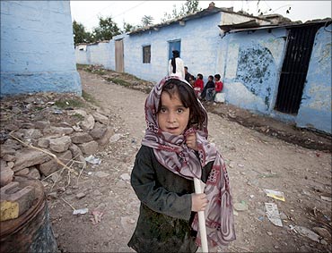 Seven-year-old Shamsa stands outside her house in a village in Noor Pur Shahan.