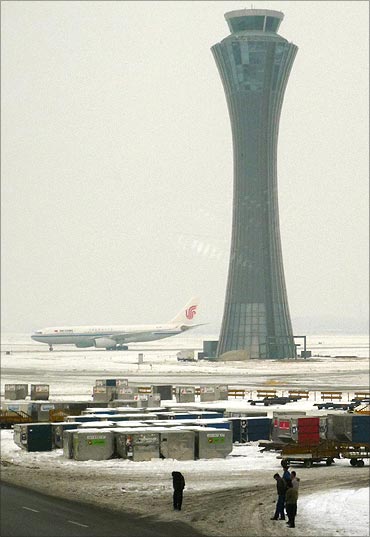 Airport workers standing out on the snow-covered tarmac at Beijing airport.