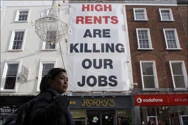 A pedestrian walks past sign protesting against high rents on Grafton Street in Dublin.
