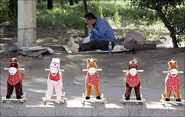 Toy horses are displayed for sale as a vendor smokes in the background on a street in Taiyuan.