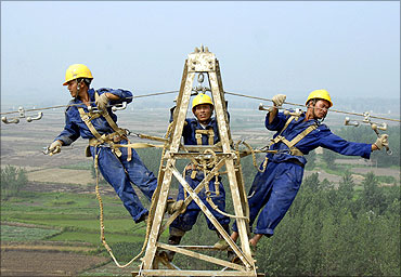 Labourers repair electricity cables on a power tower in Chuzhou.