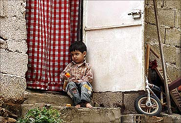 A boy sits on the front steps of his house in a slum in Algiers.