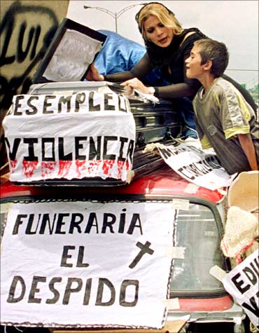 Two citizens of Medellin protest over an improvised coffin against the unemployment in Columbia.
