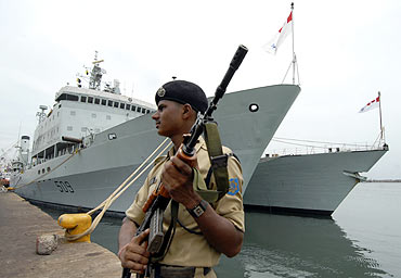 A security force personnel stands guard near the docked Canadian warships in Chennai Port