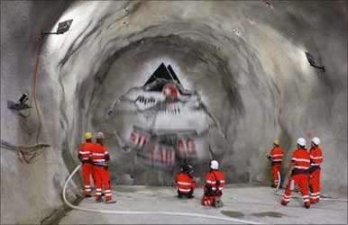 Miners watch as the ''gaby'' drill breaks through the rock at the construction site of the Gotthard Base Tunnel on June 16, 2009.
