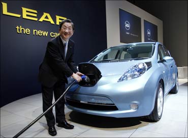 Nissan Motors COO Toshiyuki Shiga demonstrates how to recharge Nissan's Leaf all-electric vehicle.