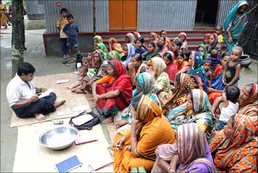 Women wait for a volunteer to distribute their loan money collected from a microfinance agency.