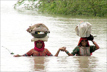 Villagers travel through heavy rain waters in the district of Kutch.