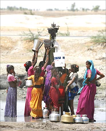 Women fill their buckets with drinking water that is leaking from a broken pipeline at Dharji.