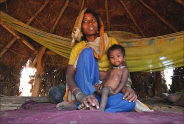Sushila, who weighs 4.5 kg and suffers from severe malnutrition, sits in her mother's lap.