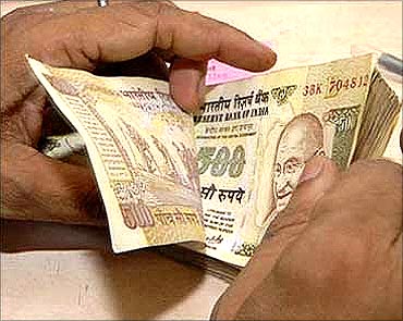 A bank employee counting rupee notes.