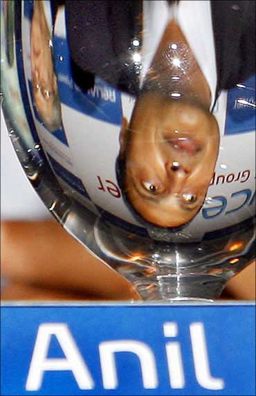 Anil Ambani is reflected in a glass while speaking to journalists.