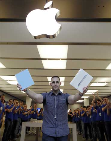 The first Madrid customer to buy an iPad 2 tablet is applauded by Apple staff at a store.