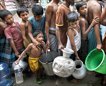Children wait in a queue to collect water distributed by the army at the Jatrabari area in Dhaka.