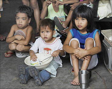 Children hold their bowls as they wait for free meals during a feeding program, Tondo, Manila.