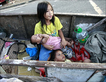 Children rest in a wooden cart after their shanty was burnt in a fire at a slum in Quezon, Manila.