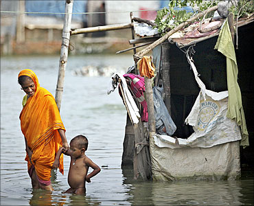 A woman wades through stagnant water with her child in the outskirts of Dhaka.