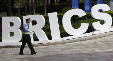 A policeman walks past a signage decoration for BRICS Summit outside Sheraton Hotel, venue of BRICS Summit in Sanya, China.