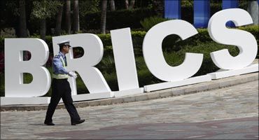 A traffic policeman walks past a signage decoration for BRICS Summit outside the Sheraton Hotel, Sanya.