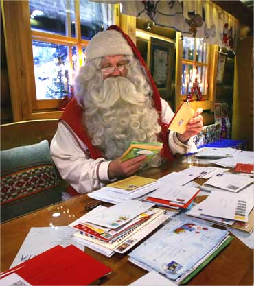 A man dressed as Santa Claus looks over letters received at the Santa Claus Office in Rovaniemi, Finland.