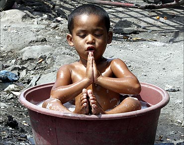 A boy plays while taking a bath in a basin at a slum in Manila.