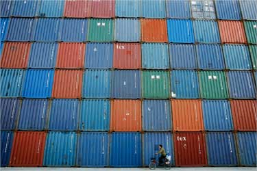 A man rides a bicycle past containers at a port in Shanghai.