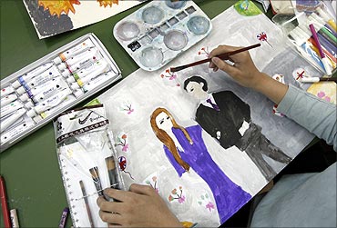 A pupil paints a picture of Britain's Prince William and his fiancee Kate Middleton at a school.