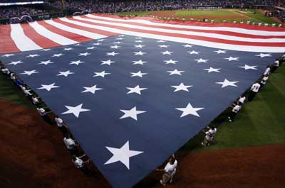 An American flag is unfurled in the outfield before the start of Game 3 of Major League Baseball's ALCS playoff series between the Cleveland Indians and the Boston Red Sox in Cleveland.