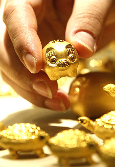 An employee of a jewellery shop holds a gold pig.