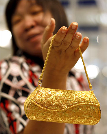 A woman shows a mobile phone purse made of gold.