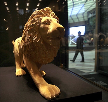 A gold statue of a lion is displayed at a jewellery shop.