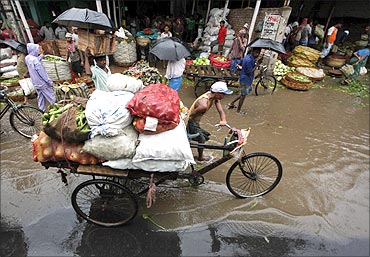 A man transports vegetables through a wholesale market during a downpour in Kolkata.